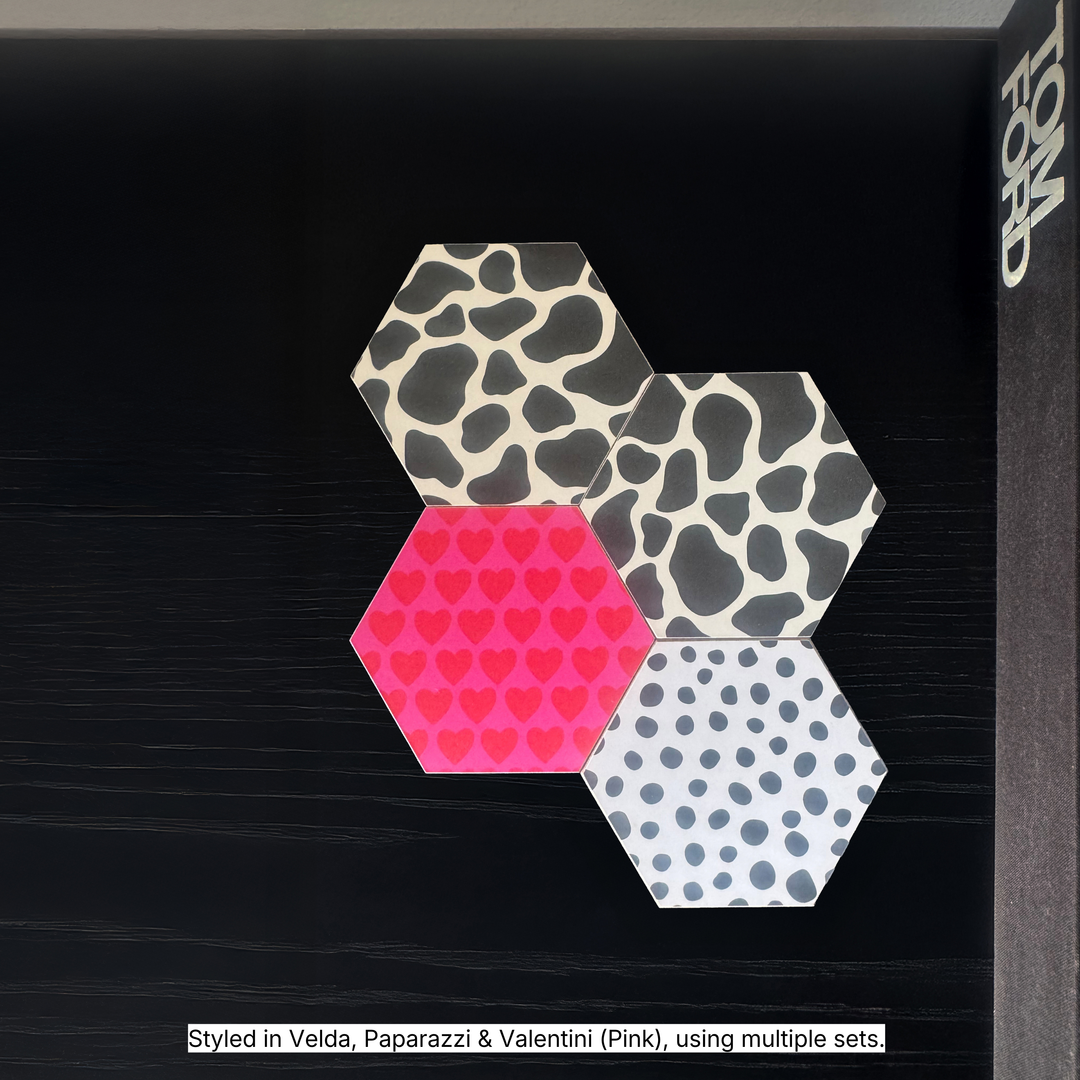 Hexagonal coasters in Velda cow print, Valentini pink and red heart print and Paparazzi polka dot print tessellated on a black surface