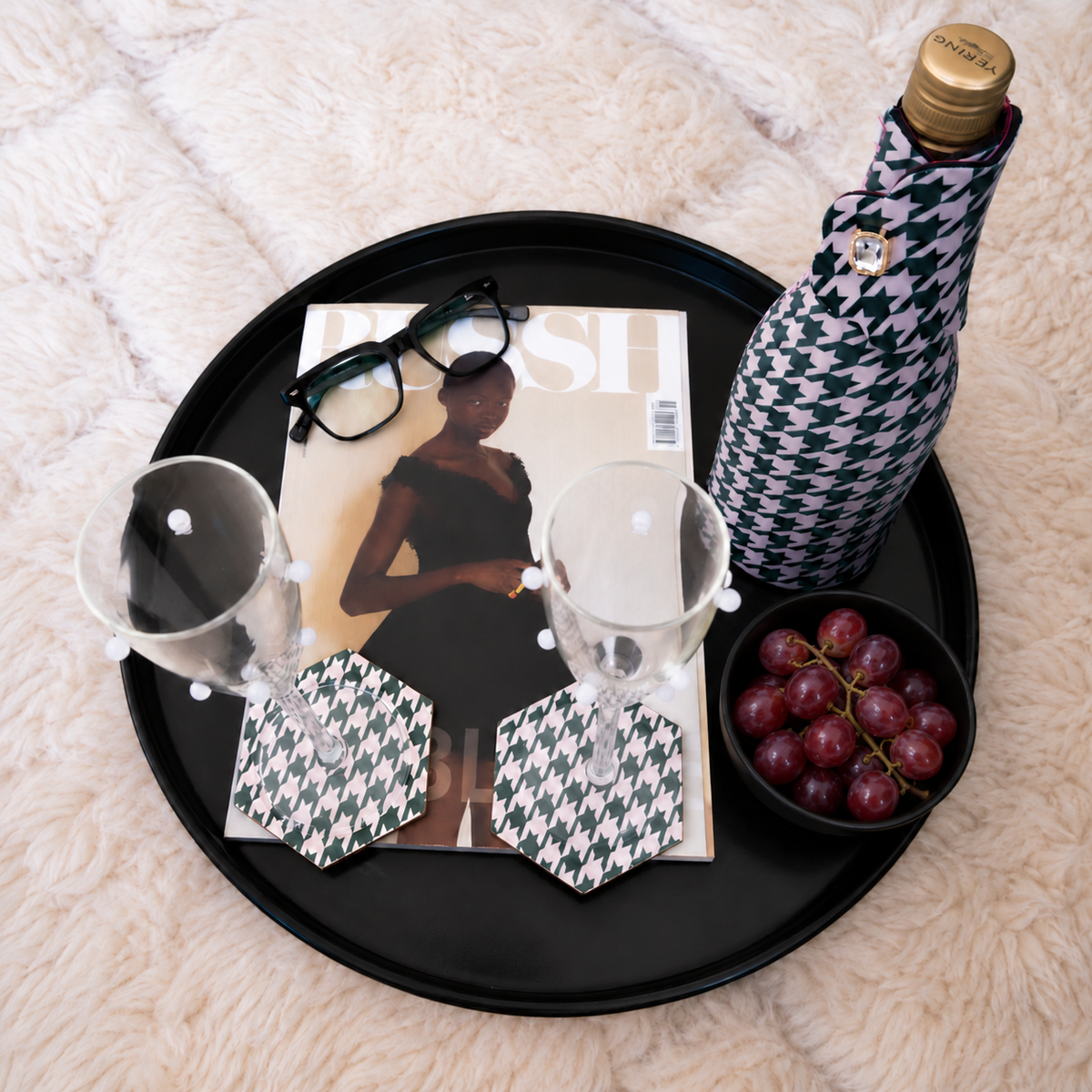 Bottle Couture wine bottle cooler and Style Tiles coasters in houndstooth print on a black tray with a magazine and red grapes