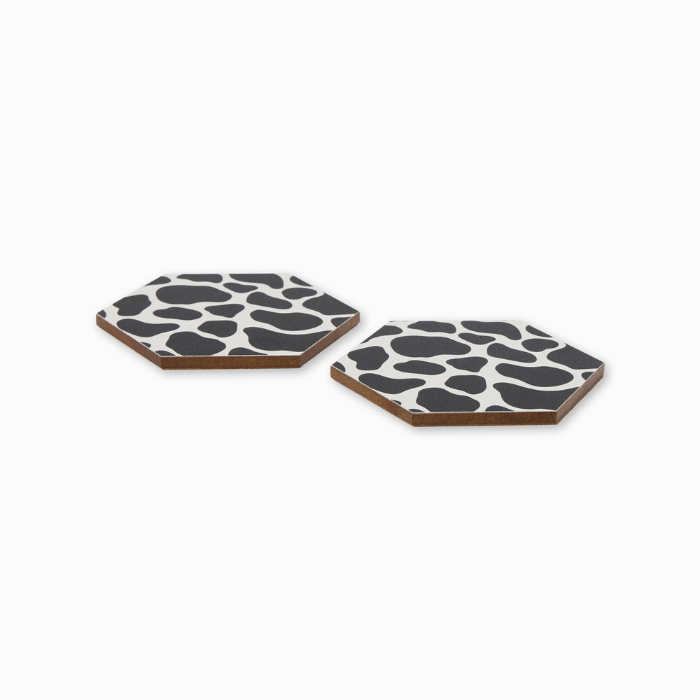 Two cow print hexagonal coasters shown from side angle