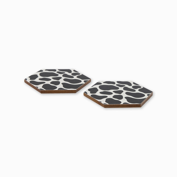 Two cow print hexagonal coasters shown from side angle