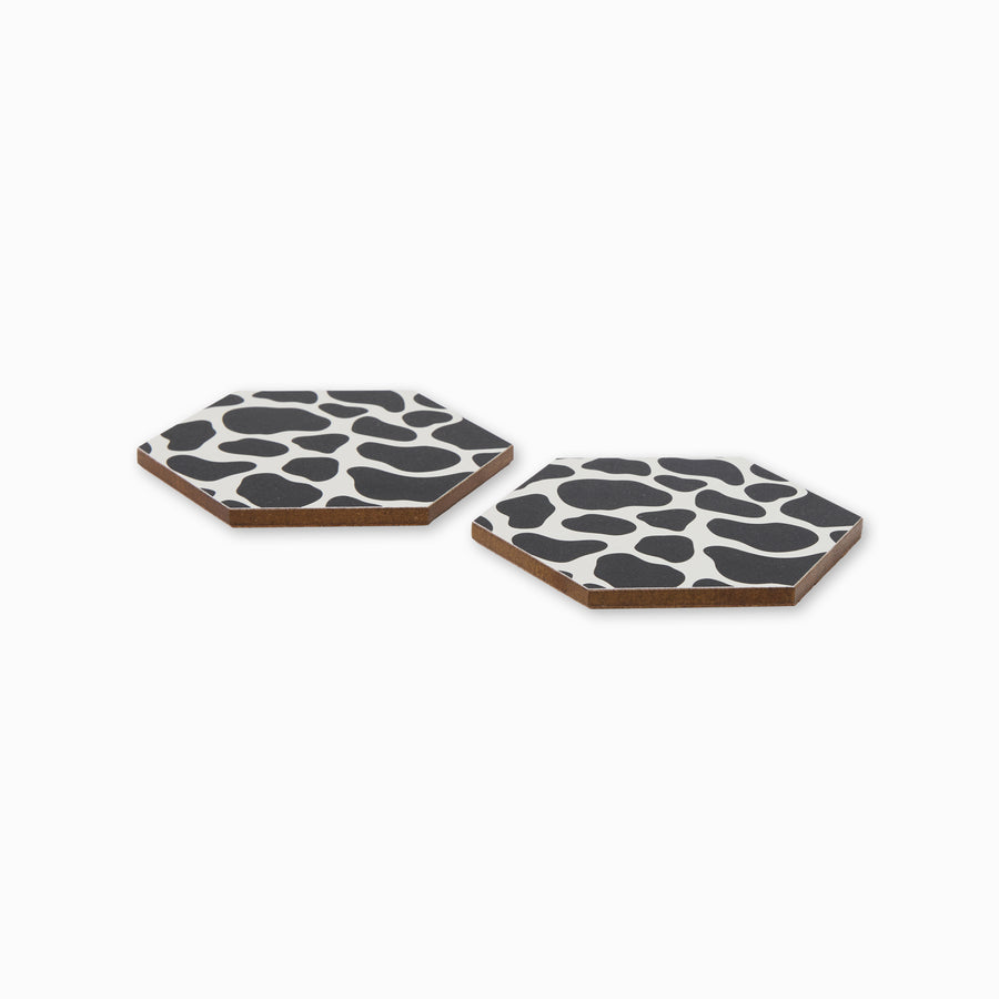 Two cow print hexagonal coasters shown from side angle