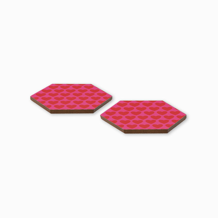 Two pink and red heart print hexagonal coasters shown from side angle