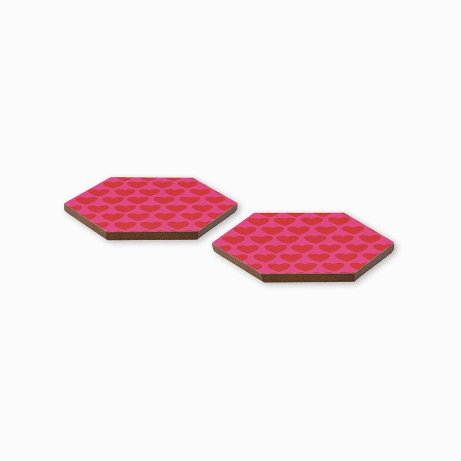 Two pink and red heart print hexagonal coasters shown from side angle